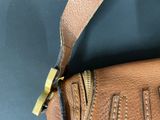 brown leather handbag with zippers on a black surface
