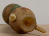 a close up of a vase with a handle on a table