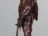 bronze statue of a man with a gun and a hat