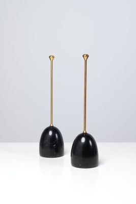 une paire de bougies noires et dorées posées sur une table blanche
