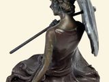bronze statue of a woman with an umbrella sitting on a leaf