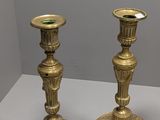 une paire de bougeoirs anciens en laiton posés sur une table blanche