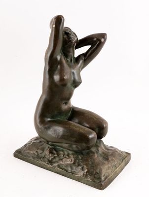 l'image d'une statue de bronze représentant une femme assise sur un rocher