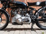 a black motorcycle parked on a brick sidewalk next to a brick wall