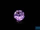a close up of a purple diamond on a black surface