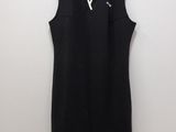 a black dress hanging on a hanger against a white wall