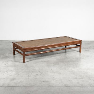 une table basse en bois avec un plateau en verre, posée sur un sol en béton
