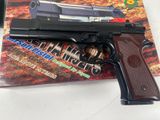 gun on a table next to a magazine on a white surface