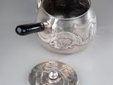 a silver tea pot with a lid on a table
