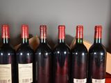six bottles of red wine are lined up on a table