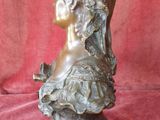 bronze bust of a woman wearing a headdress on a red background