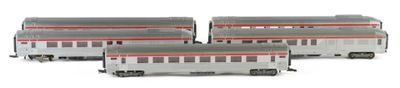 three silver and red train cars sitting next to each other on a white surface