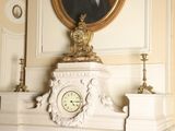 a clock on a mantle in a room with a painting on the wall