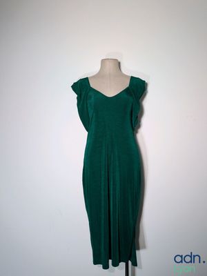 une robe verte posée sur un mannequin contre un mur blanc