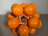 an orange sculpture made out of wooden balls on a table
