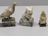 three statues of birds sitting on top of a table next to each other