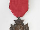 une ancienne médaille avec un ruban rouge sur fond blanc