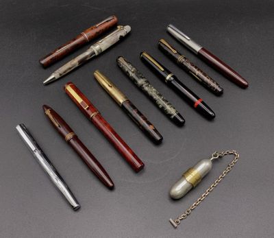 six stylos différents et une chaîne posés sur une surface noire