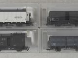 quatre boîtes en plastique contenant quatre types de trains différents, posées sur une surface blanche
