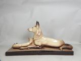 figurine of a dog laying down on a wooden base