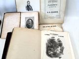 several old books sitting on top of a white table next to a cup of coffee