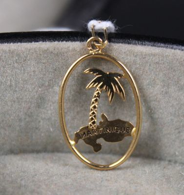 a gold plated pendant with a palm tree on it