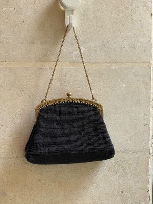 le sac à main noir est accroché au mur, à côté du mur