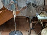 deux ventilateurs métalliques posés par terre l'un à côté de l'autre