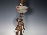 une lampe à l'ancienne sur laquelle est représenté un homme tenant une épée et un abat-jour