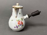 a small white tea pot with flowers on it