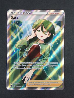 un gros plan sur une carte Pokémon représentant une fillette en robe verte