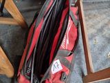 un sac de voyage rouge posé par terre à côté d'une paire de ciseaux