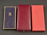 three red and purple boxes with a gold monogram on them