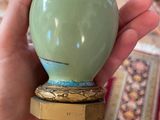 a person holding a green vase in their hand