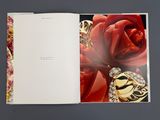 an open book with a picture of a red rose and a pair of earrings