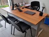a desk with a laptop and two chairs in front of a window