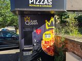 un distributeur automatique sur lequel est posée une pizza, au milieu de la rue