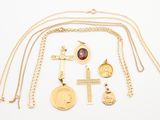 plusieurs colliers et pendentifs en or posés sur une surface blanche