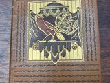 brown leather box with a bird on it sitting on a wooden table