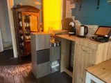 une petite cuisine avec une armoire en bois et un ordinateur portable posé sur le plan de travail