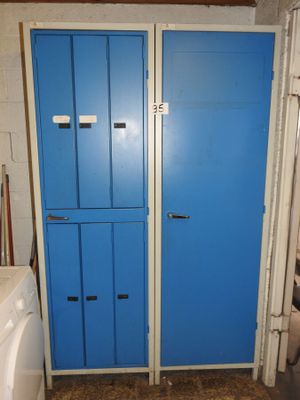 deux armoires bleues dans une petite pièce où se trouvent une machine à laver et un sèche-linge