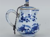une théière bleue et blanche entourée d'une chaîne