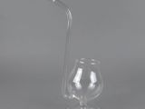 a clear glass with a straw and a glass cup on a gray background