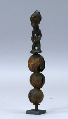 une image représentant une sculpture en bois représentant une personne assise sur une boule