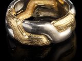 un gros plan d'une bague en or et en argent sur une surface noire