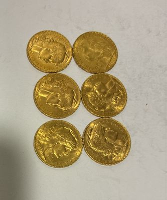 six gold coins sitting on top of a table next to a bottle