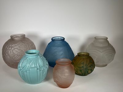 cinq vases de couleurs différentes posés sur une surface blanche
