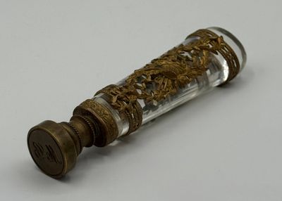 une petite bouteille en verre ornée d'un motif doré