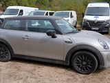 a silver mini cooper parked in a lot with other cars