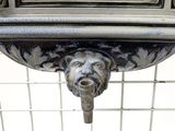 a metal sink with a lion head on top of it